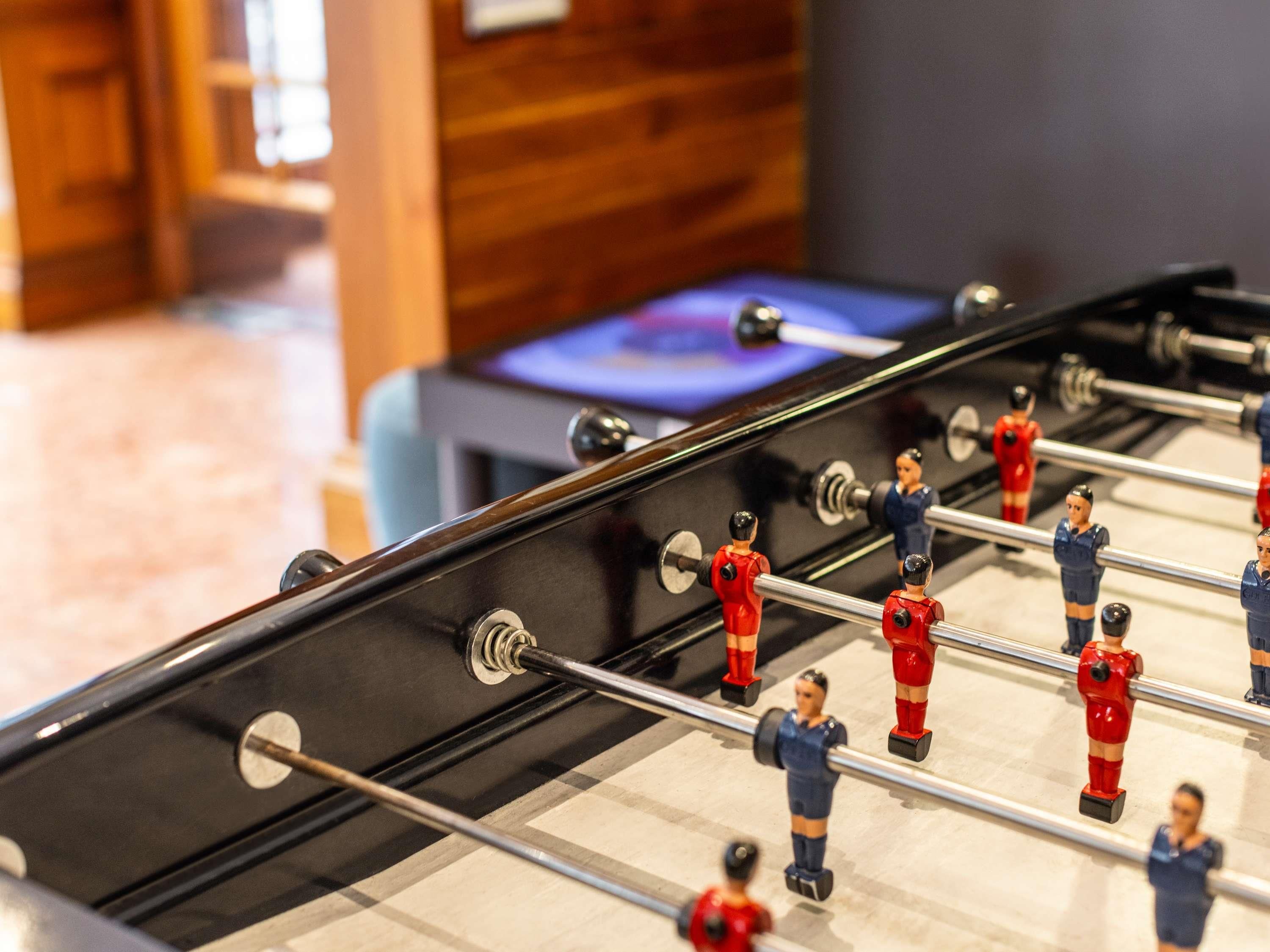 Taula de futbolí amb jugadors uniformats de vermell i blau.