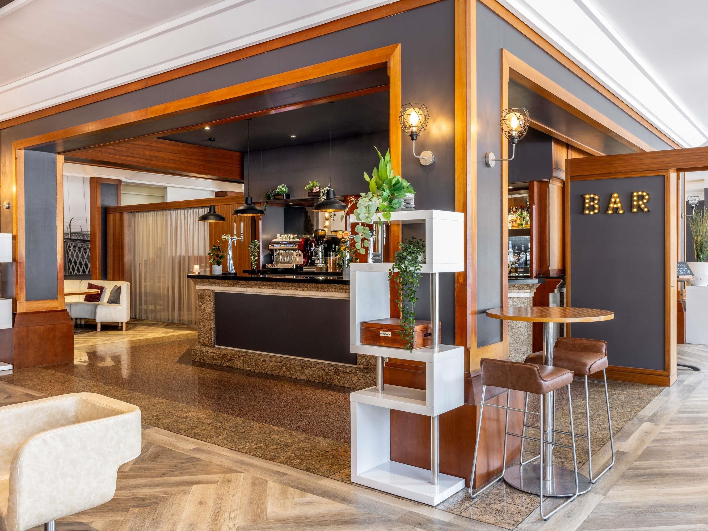 A modern bar area with a counter, bar stools, and a sign that reads "BAR".