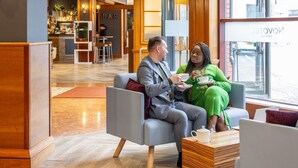 A modern hotel lobby with a bar area, seating, and a view of the street. - Novotel Bristol Centre (Bristol)