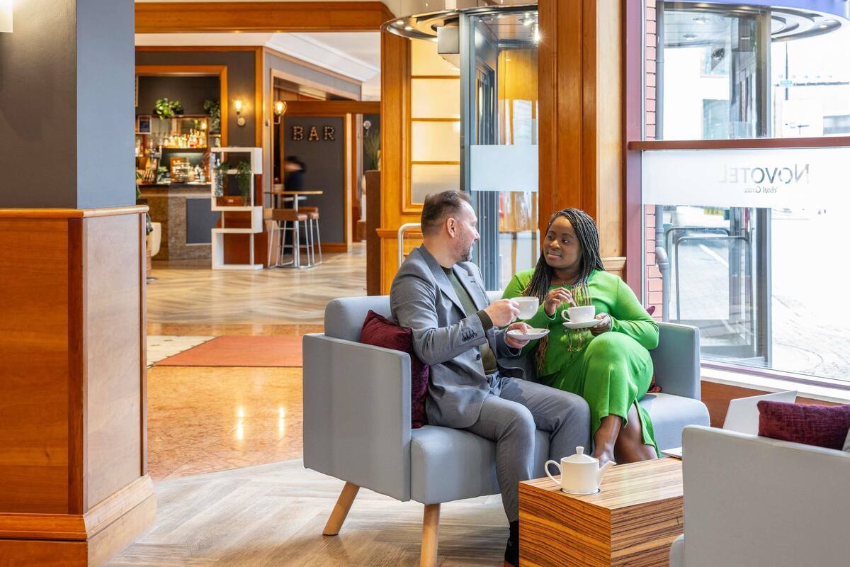 A modern hotel lobby with a bar area, seating, and a view of the street.