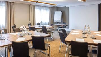 A conference room with multiple tables, chairs, a projector, and a whiteboard.