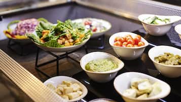 Un buffet proposant une variété de plats, notamment des salades, des légumes et des sauces.