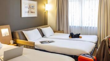 Habitación de hotel con dos camas, un escritorio con una computadora portátil, un cuadro en la pared y una ventana con cortinas.