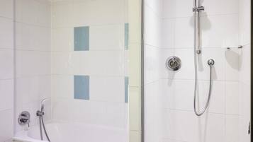 Un baño con bañera y zona de ducha, ambos con paredes de azulejos blancos y un diseño moderno.