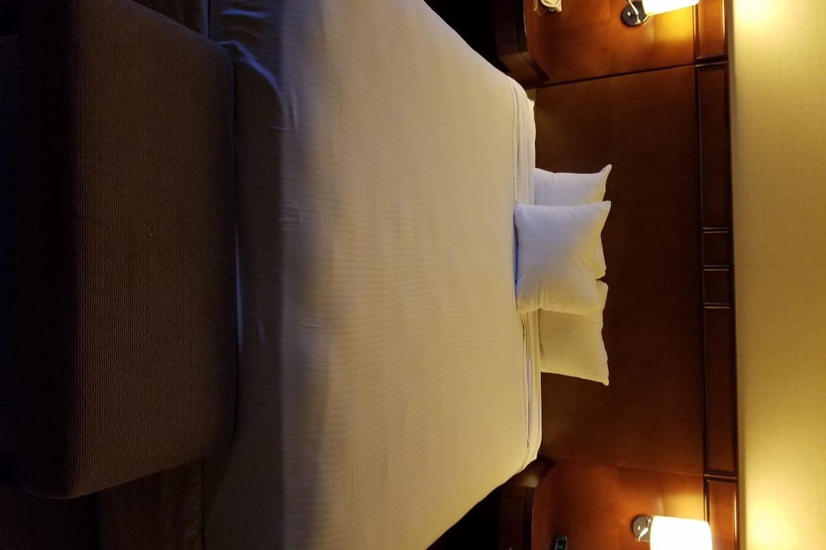 A hotel room with a bed, a nightstand, and two bedside lamps.