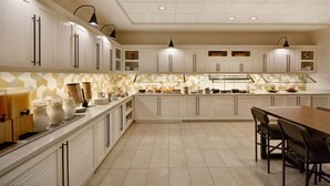 A modern kitchen with white cabinets, a central island, and pendant lighting.