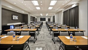 A conference room with rows of tables, chairs, and water bottles.