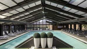 An indoor swimming pool with a high ceiling, multiple lounge chairs, and potted plants. - Hyatt Regency Princeton (Princeton)