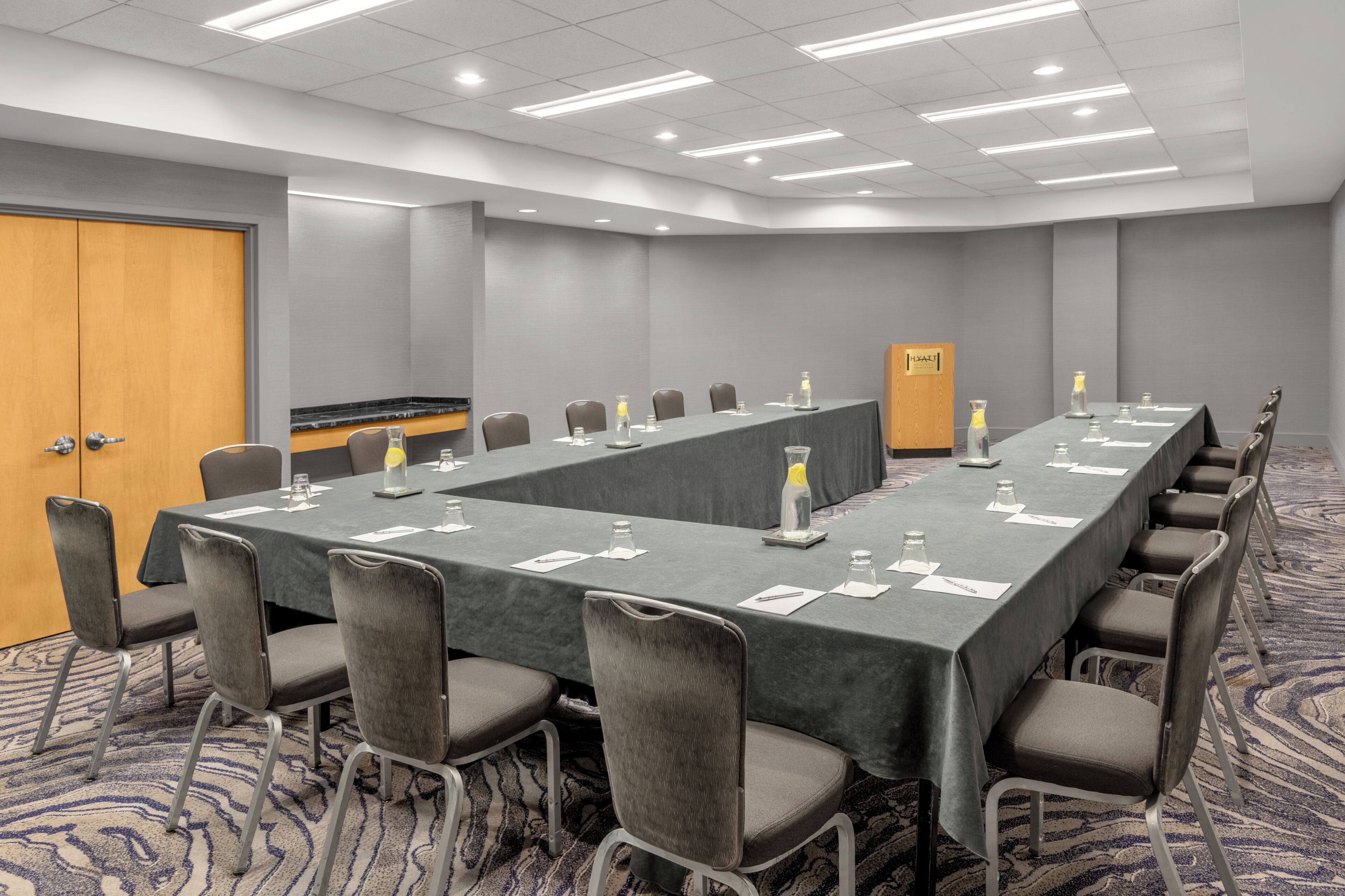 Un salón de conferencias con una larga mesa, sillas y un atril.