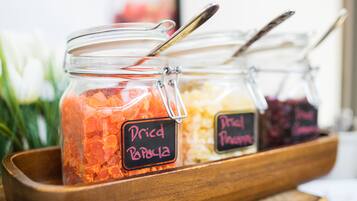 A wooden tray holding three glass jars labeled with different types of dried fruit.