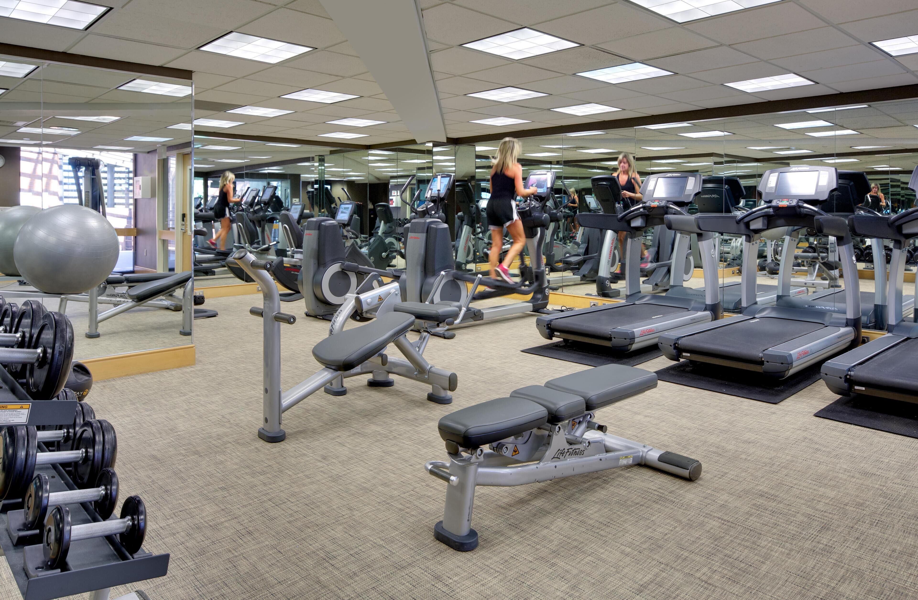 Academia com esteiras, aparelhos de musculação e bolas de exercício.