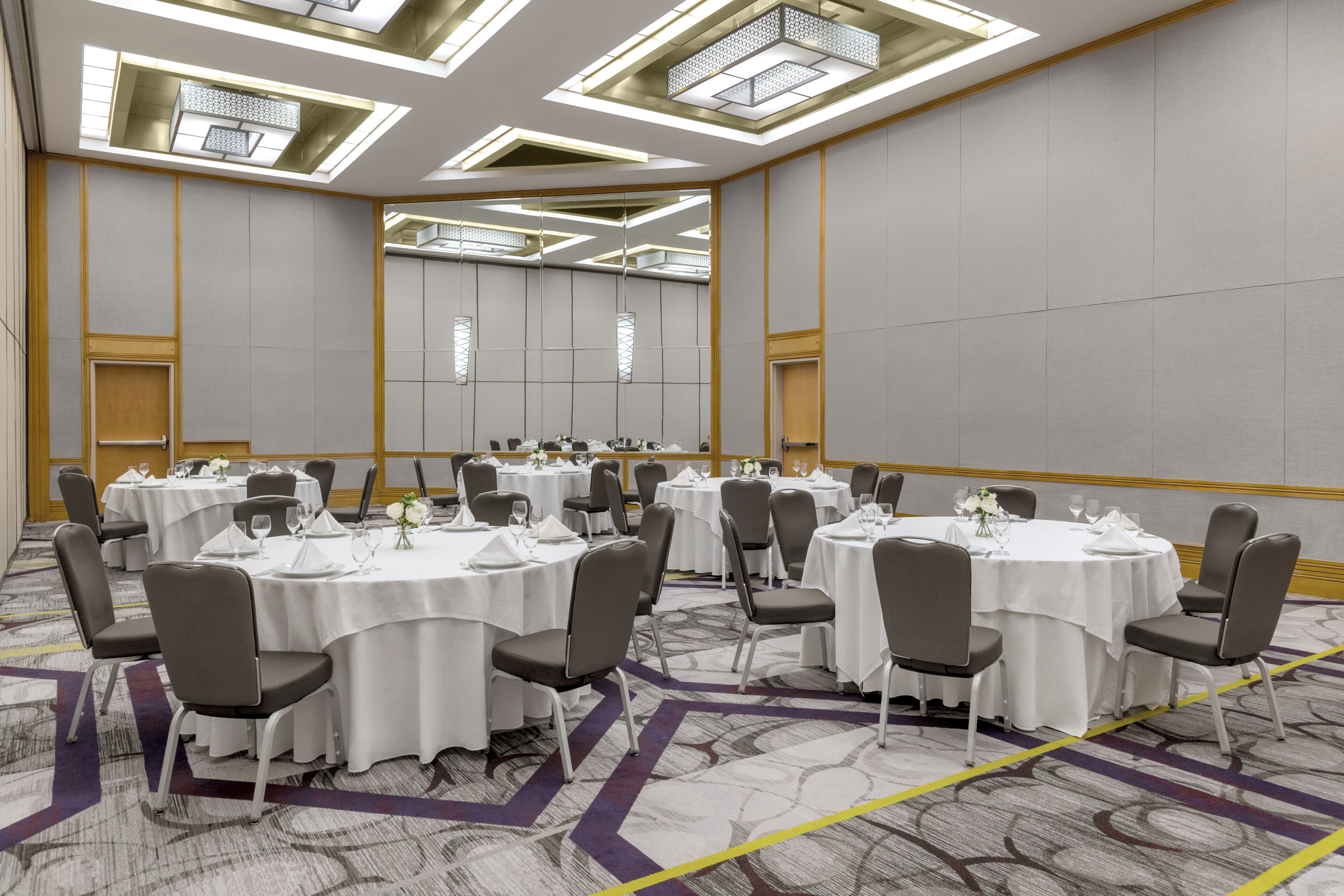 A conference room with round tables, chairs, and a carpeted floor.