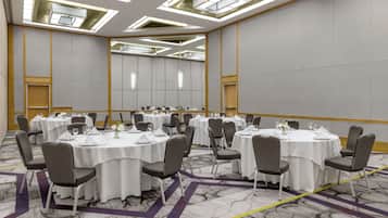 A conference room with round tables, chairs, and a carpeted floor.