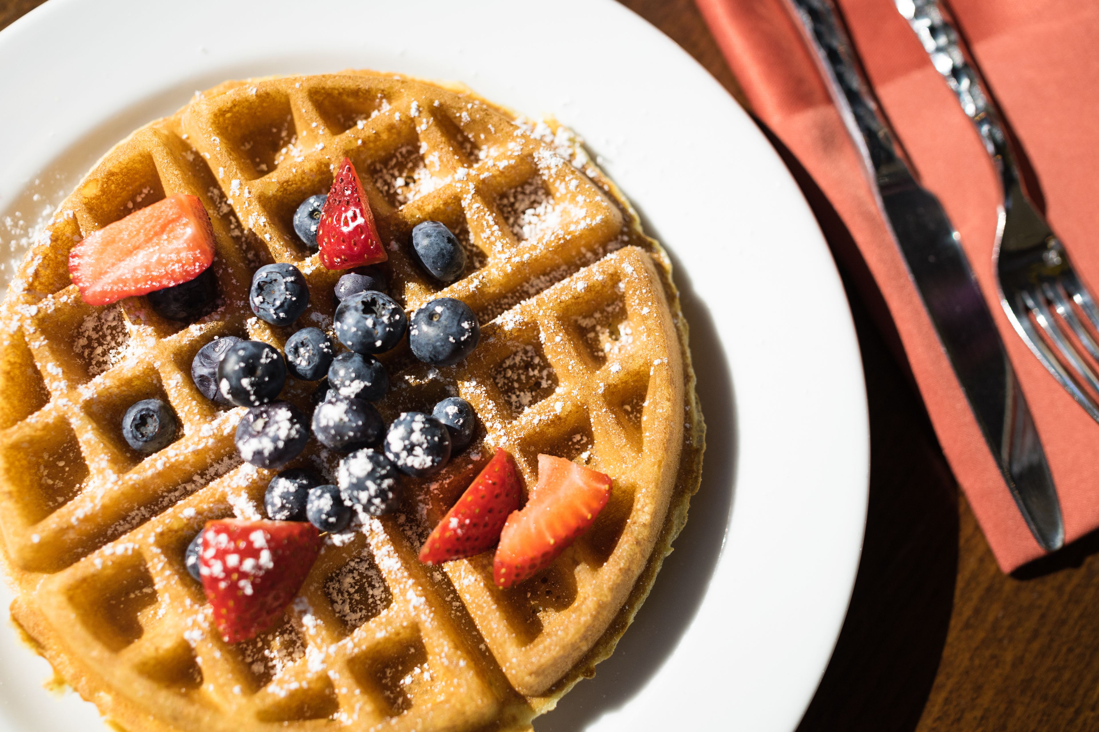 Ein Waffel mit Erdbeeren und Blaubeeren auf einem weißen Teller.
