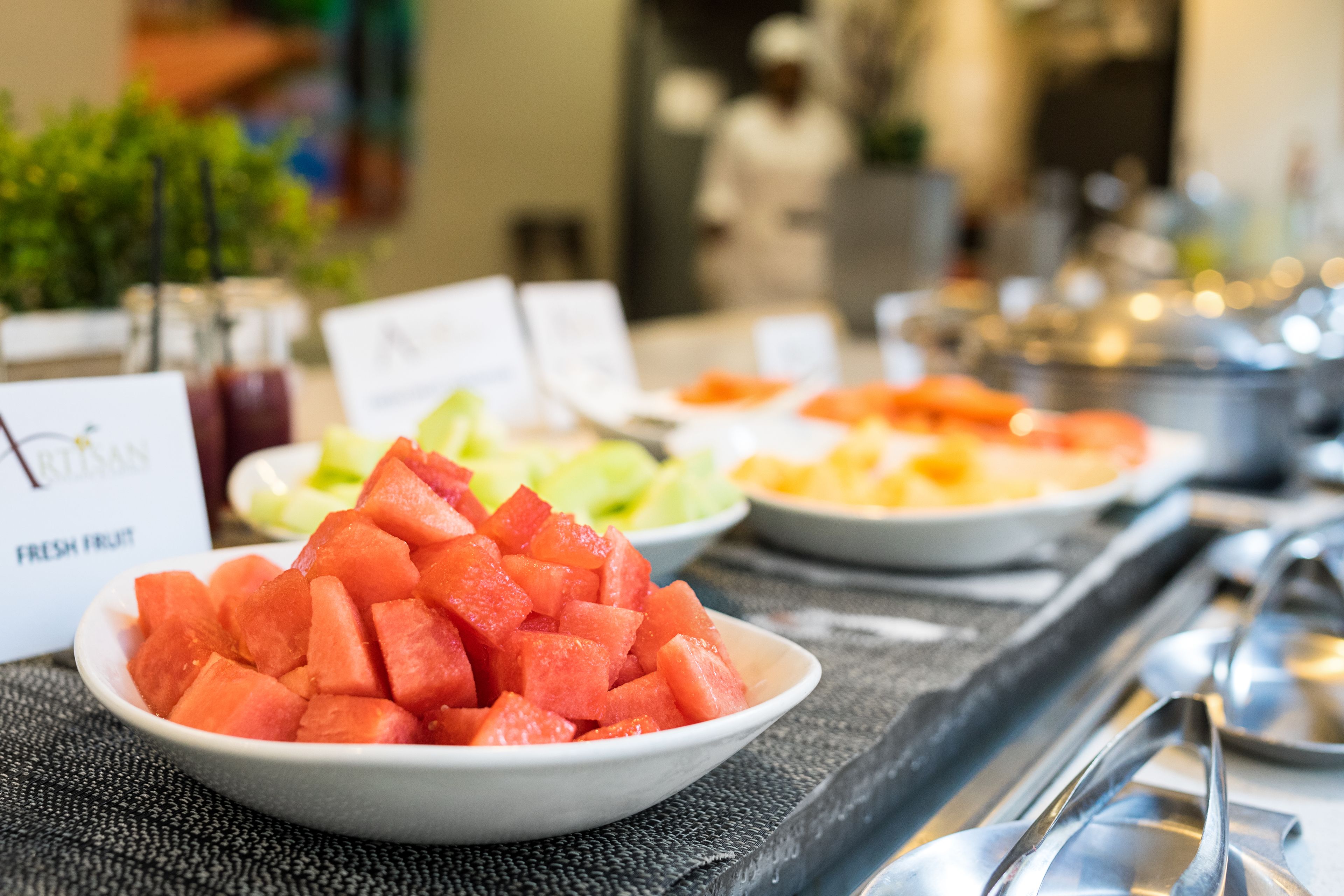 A buffet table with various fruit options including watermelon, melon, and pineapple.
