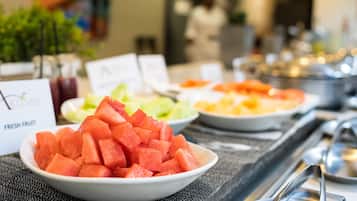 A buffet table with various fruit options including watermelon, melon, and pineapple.