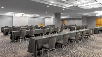 A conference room with multiple tables and chairs, carpeted floor, and recessed lighting.