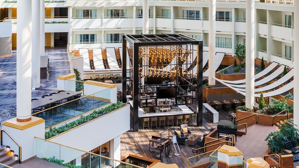 A multi-level hotel atrium with a central bar, outdoor seating, and a pool area. - Hyatt Regency Princeton (Princeton)