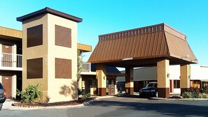 A hotel with a modern design, featuring a prominent entrance with a covered area and a parking lot.