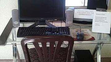 Un escritorio de vidrio con una computadora, que incluye un monitor, teclado y ratón. Hay una silla frente al escritorio.
