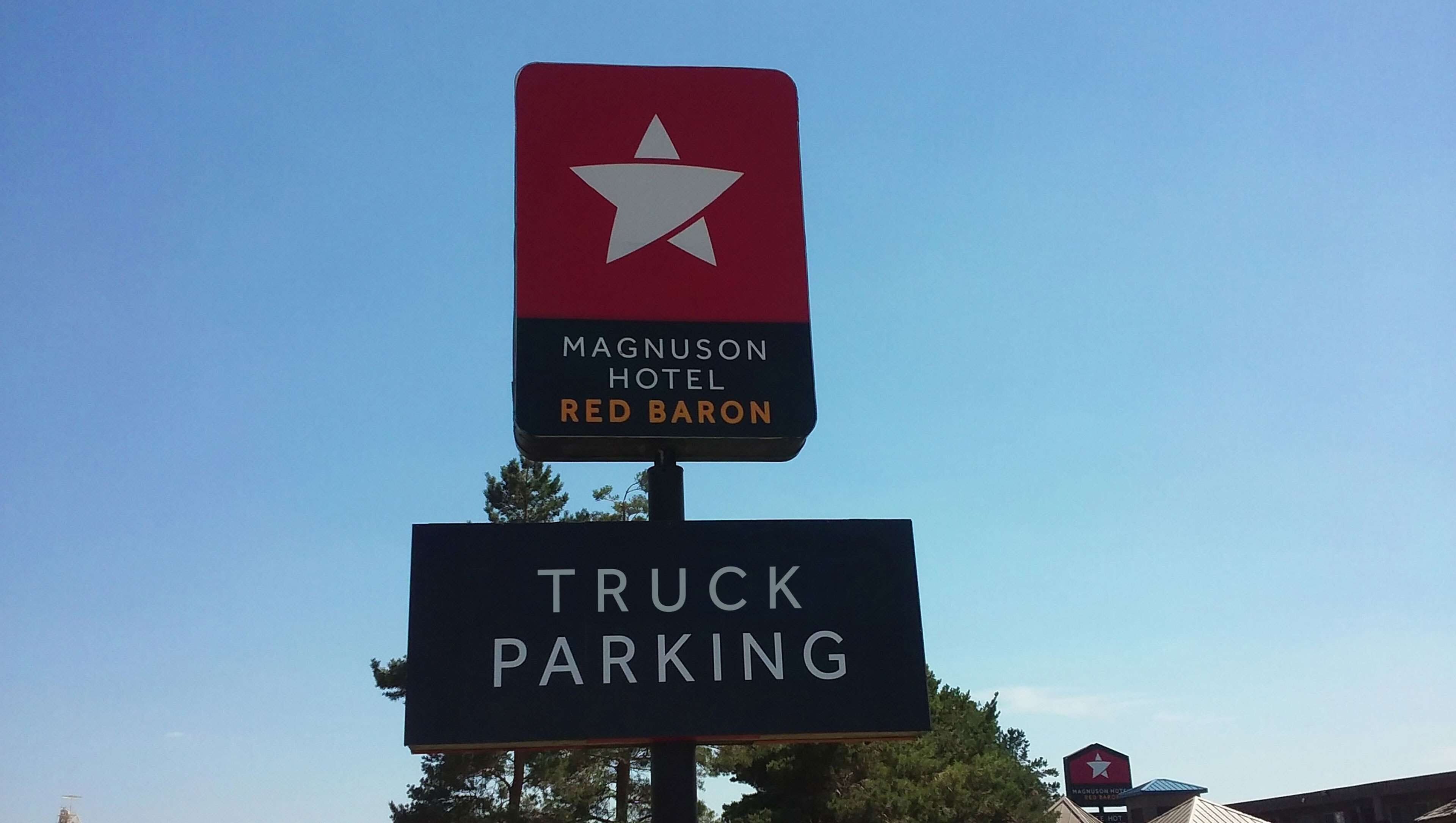 A sign for the Magnuson Hotel Red Baron with a truck parking sign below it.