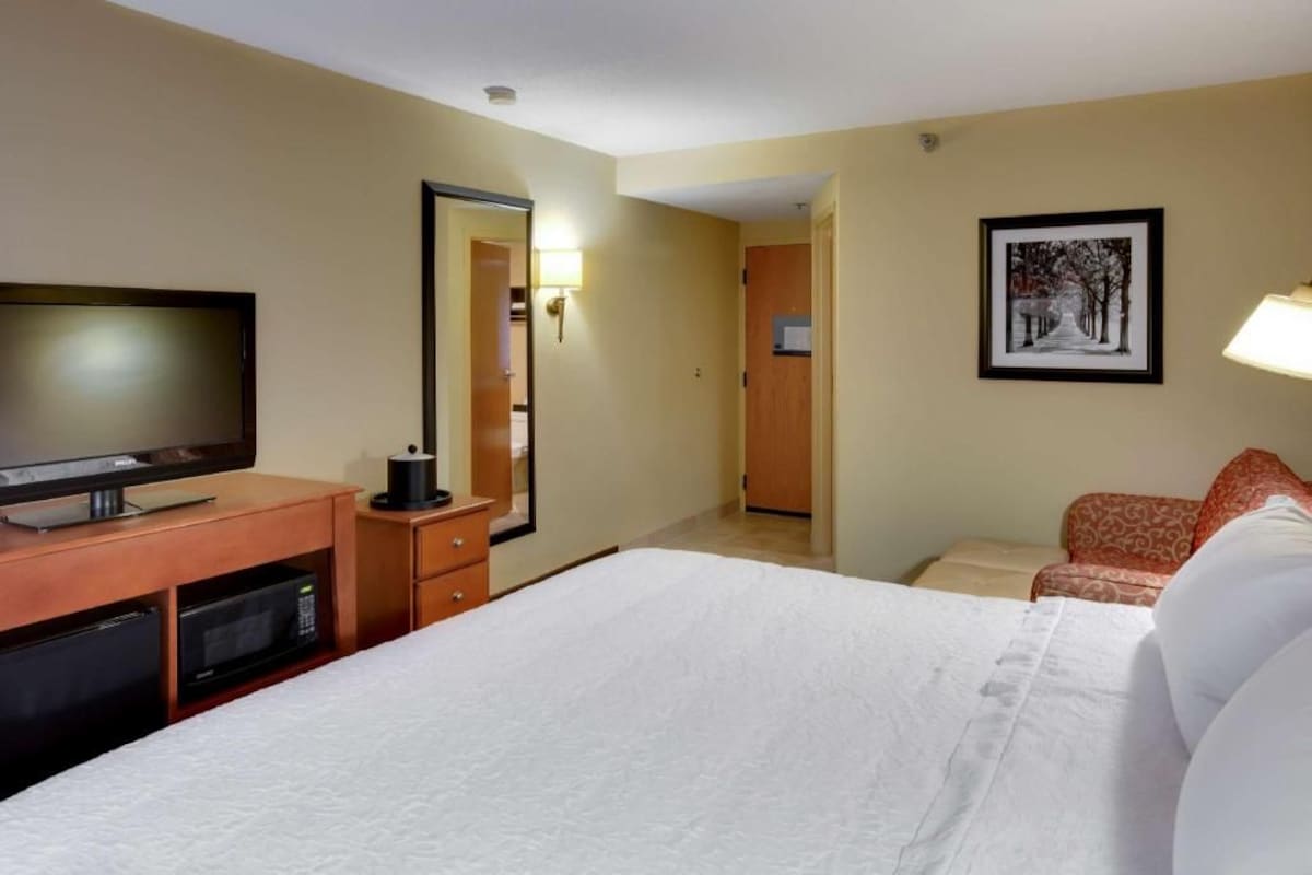 A hotel room with a bed, television, microwave, and a door leading to another room.