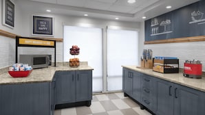 A modern kitchen with a microwave, coffee maker, and breakfast bar. There are cabinets, a sink, and a chalkboard with food illustrations. - Hampton Inn Pittsburgh/Greentree (Pittsburgh)