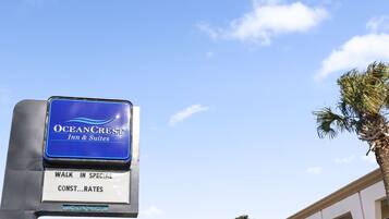 A hotel sign for Oceancrest Inn & Suites with a 'Walk in Special Rates' sign below it.