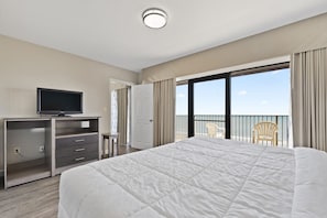 Ein Hotelzimmer mit einem großen Bett, einem Fernseher auf einem Holztisch, einem Balkon mit einem Stuhl und Blick aufs Meer.