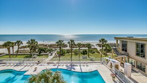 A pool area with lounge chairs, a clear view of the beach, and a building with a balcony overlooking the ocean. - Atlantic crest inn and suites (Myrtle Beach)
