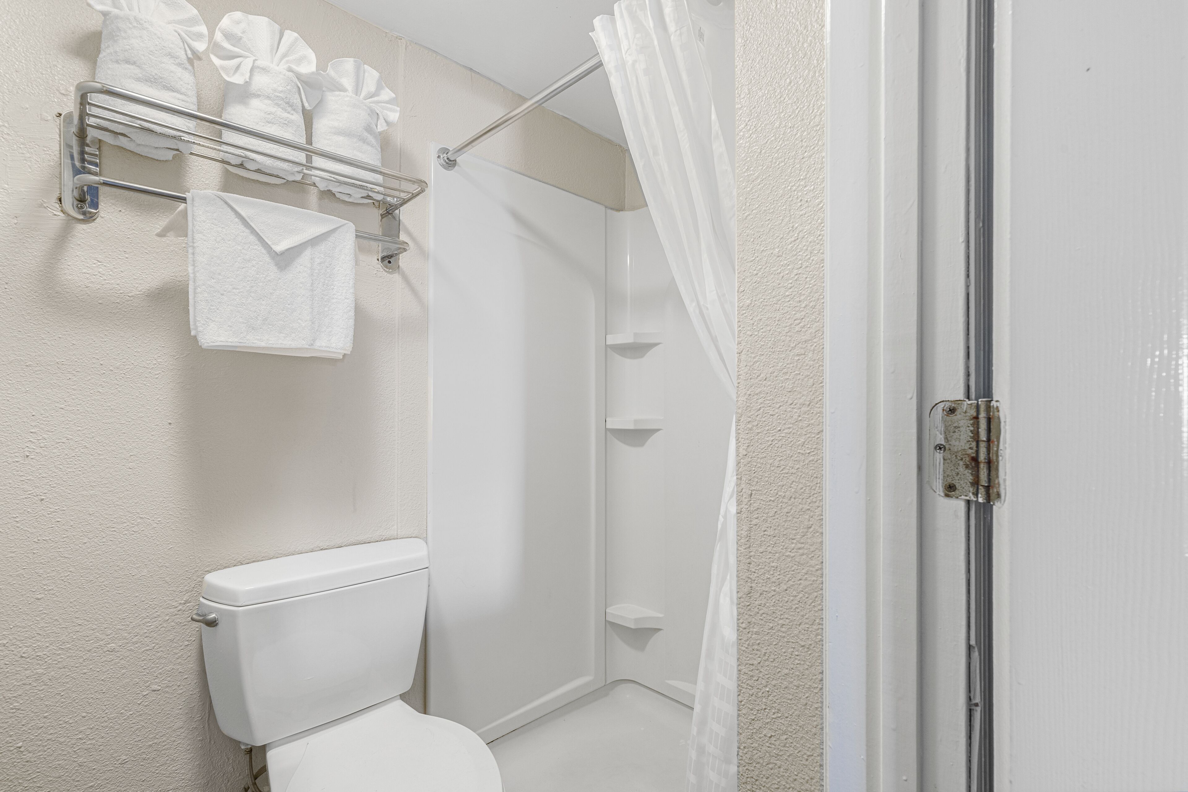A bathroom with a toilet, a shower with a glass door, and a towel rack with towels.
