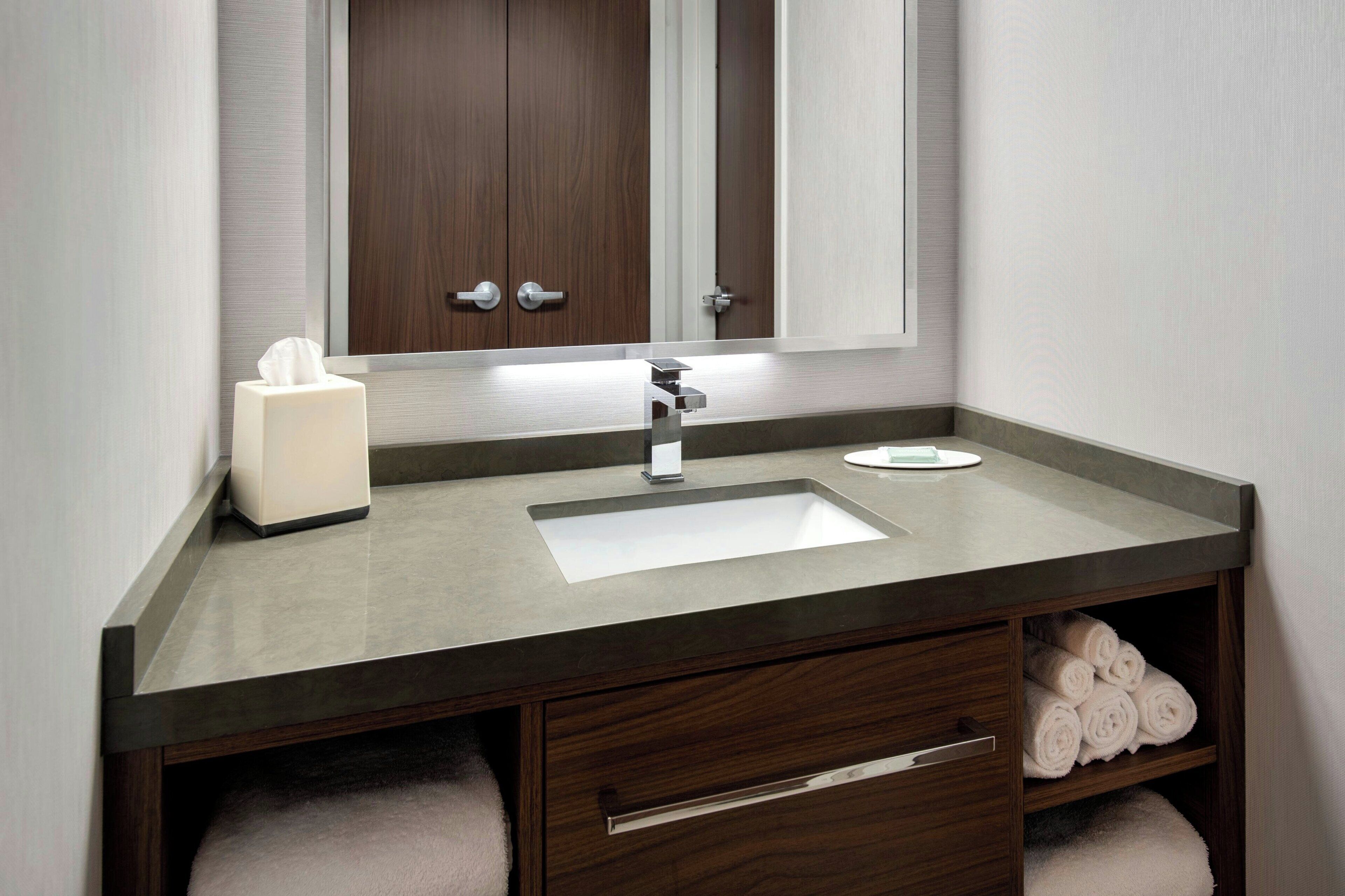 A bathroom with a large mirror, a sink, a towel rack, and a tissue dispenser.