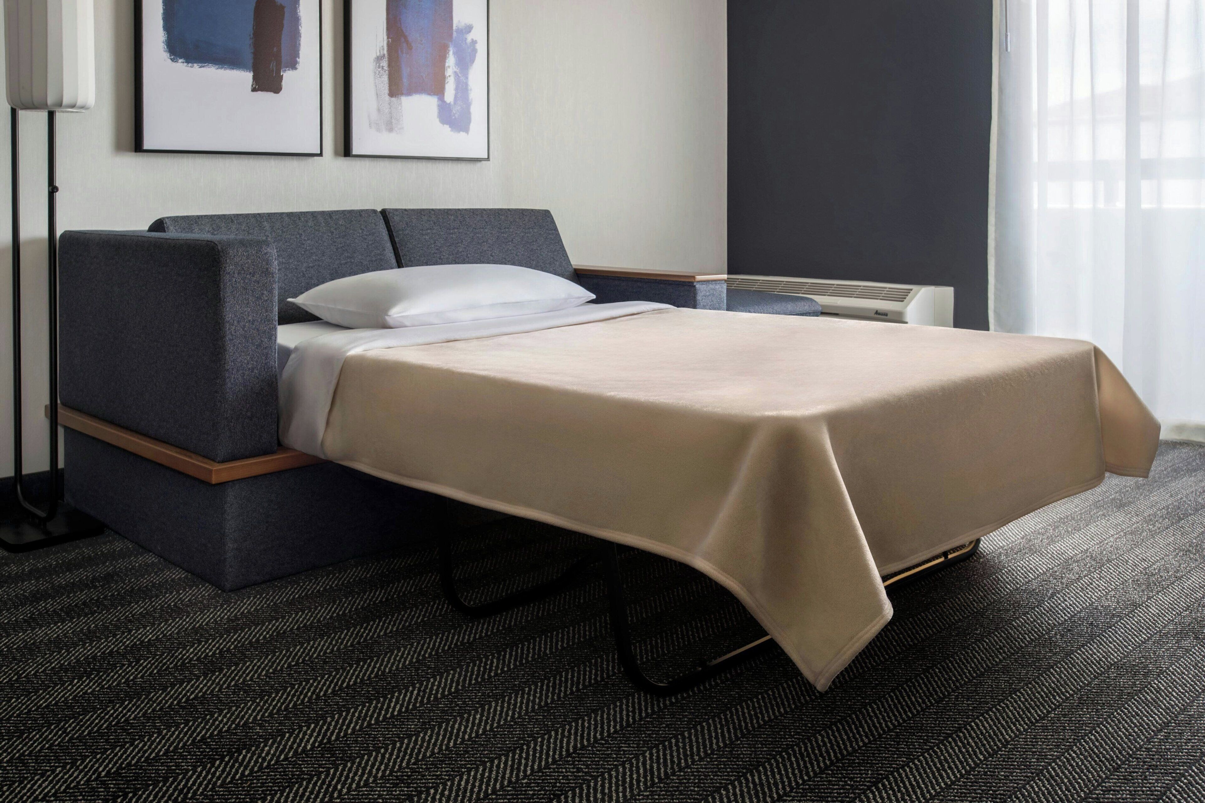 Een hotelkamer met een bed, nachtkastje, lamp en kunst aan de muur.
