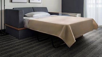 Een hotelkamer met een bed, nachtkastje, lamp en kunst aan de muur.
