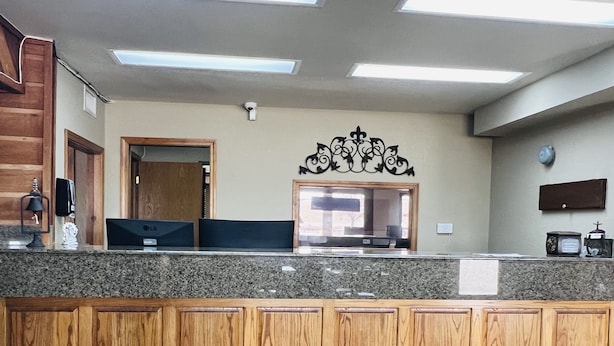 A kitchen with granite countertops, wooden cabinets, a microwave, and a coffee maker. - Cattle Country Lodge (Stroud)