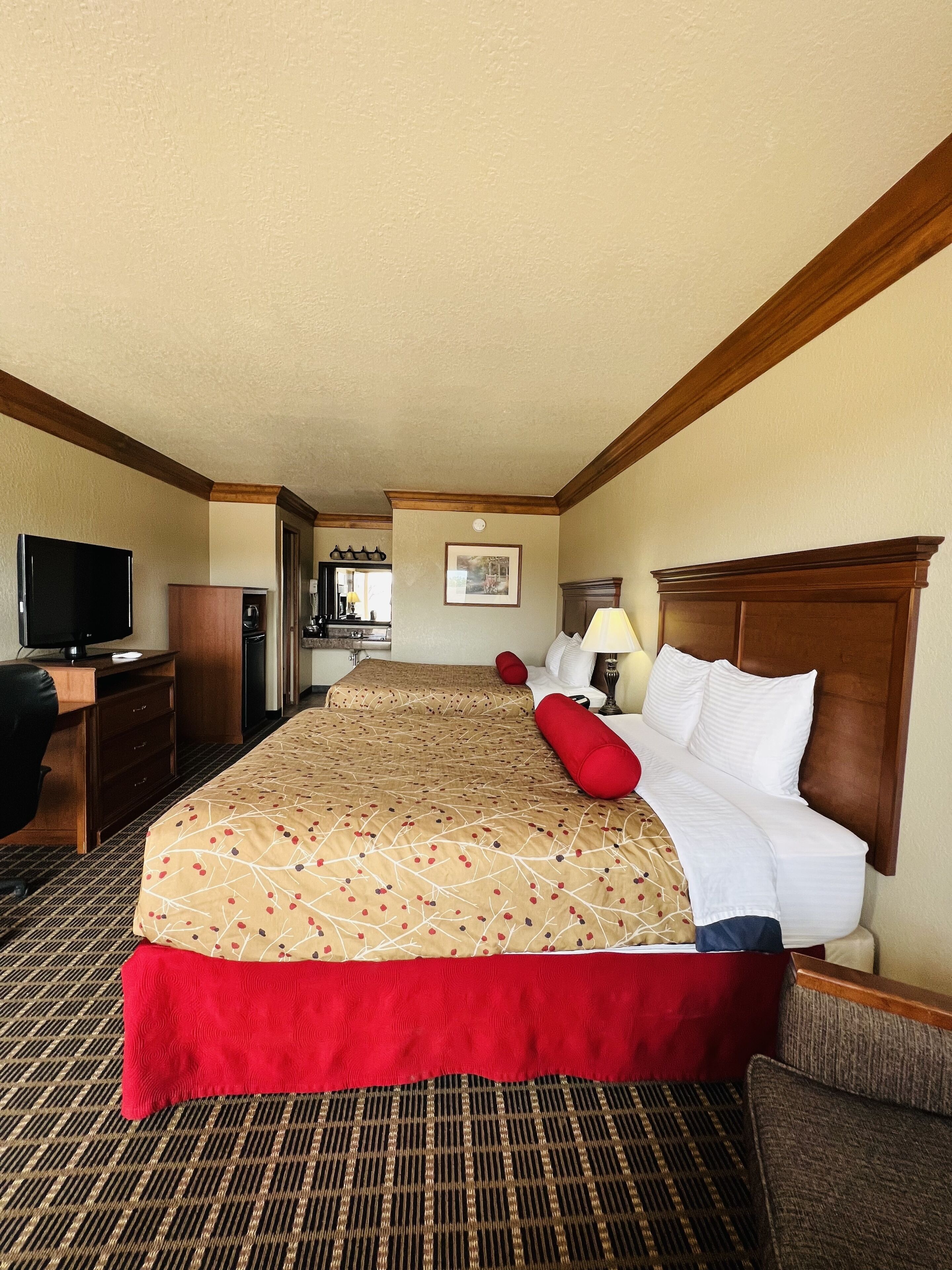 A hotel room with a large bed, a desk, a television, and a bathroom visible through an open door.