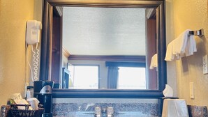 A bathroom with a granite countertop, a large mirror, and three wall-mounted lights. - Cattle Country Lodge (Stroud)