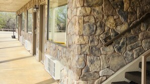 A building with a stone exterior, large windows, and a covered outdoor area with a concrete floor. - Cattle Country Lodge (Stroud)