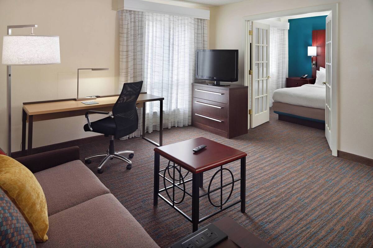 Une chambre d’hôtel équipée d’un bureau, d’une télévision, d’un lit et d’un canapé.