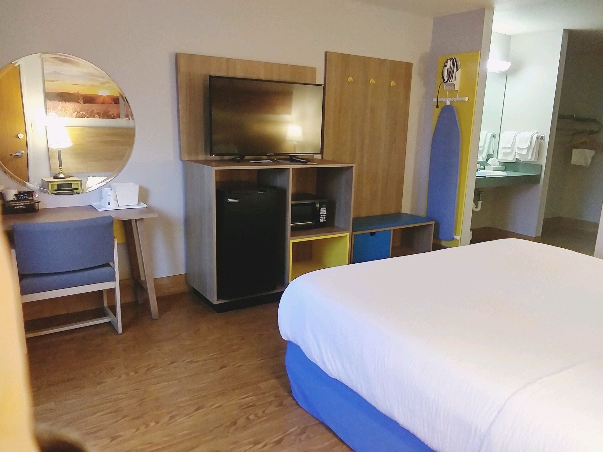Habitación de hotel con cama, escritorio con computadora, televisor y armario.