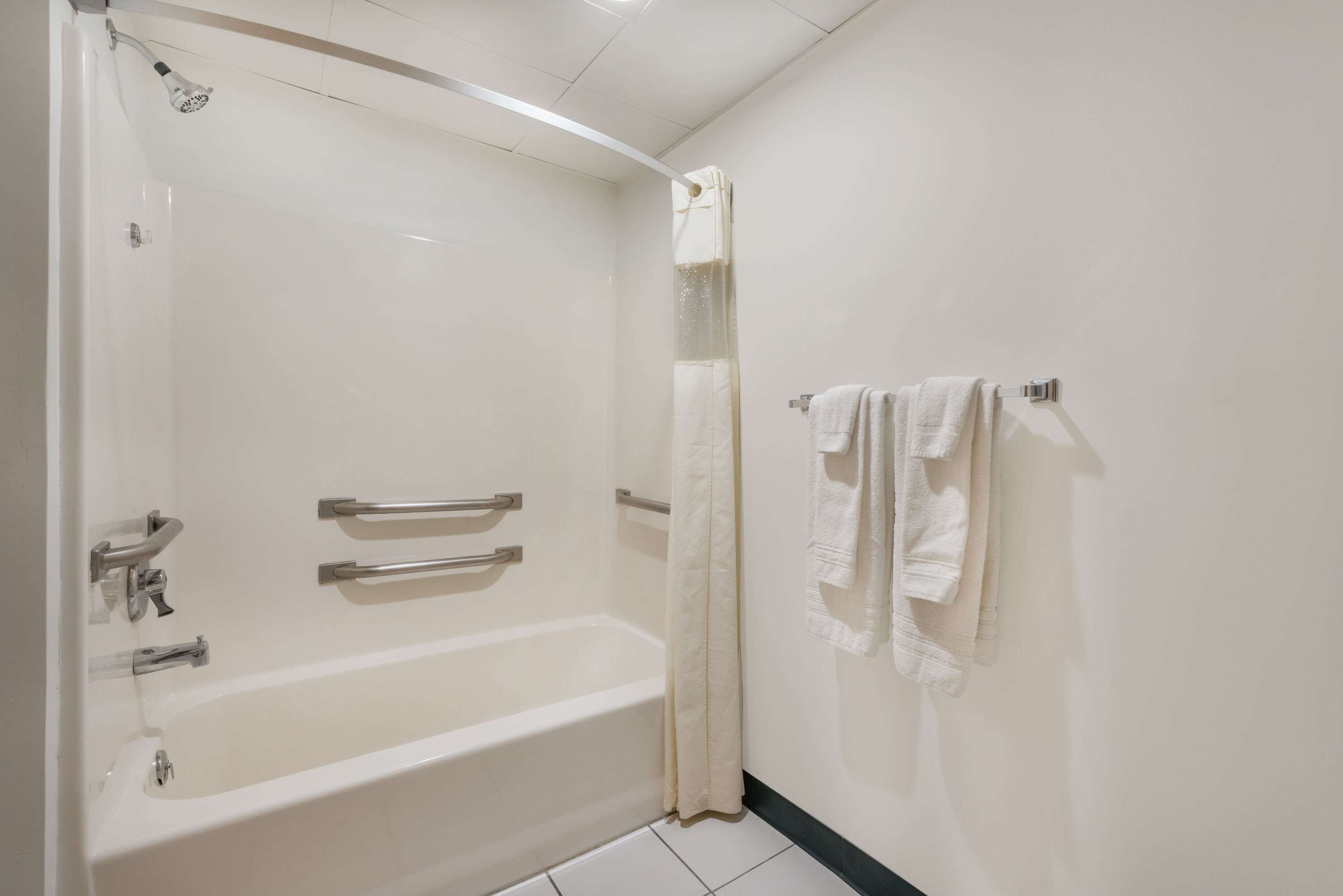 A bathroom with a bathtub, a shower curtain, and a towel rack.