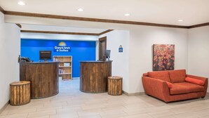 A reception area with a blue wall, wooden reception desk, and a red sofa.