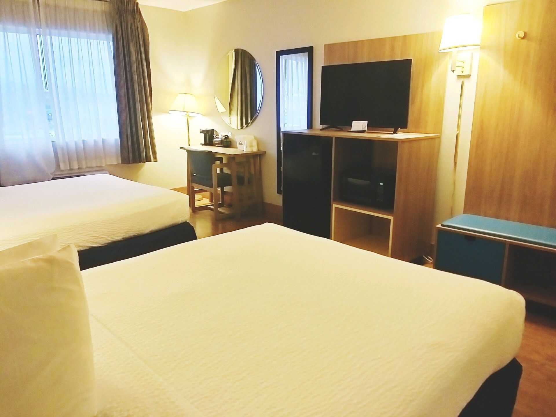 Una habitación de hotel con dos camas, un escritorio, un televisor y un armario.