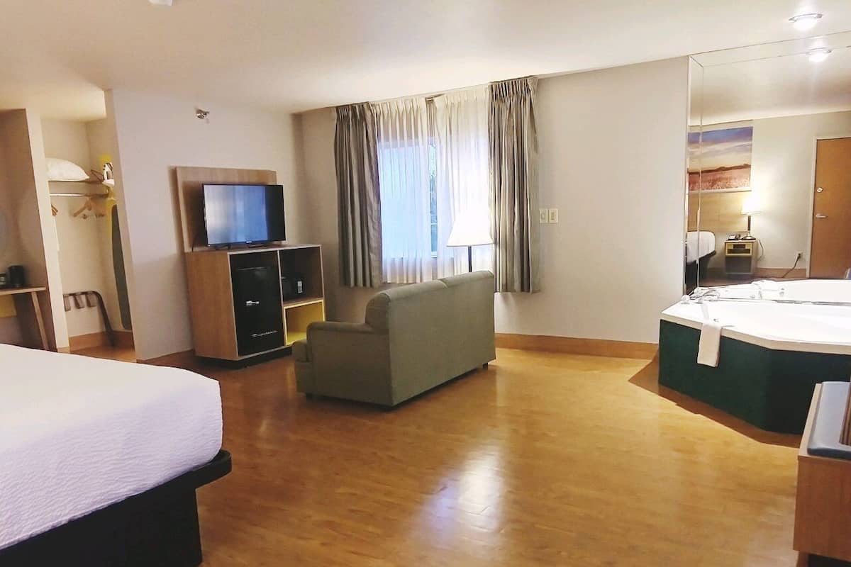 Ein Hotelzimmer mit Bett, Sofa, Fernseher, Schreibtisch und Bad.