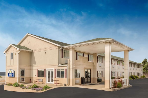 Edificio de Days Inn & Suites con un área de estar al aire libre cubierta, ventanilla de servicio y estacionamiento.