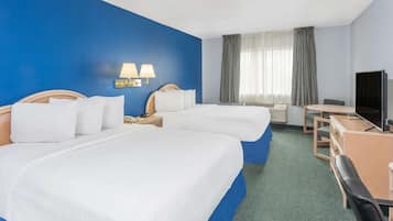 Hotelkamer met twee bedden, een bureau, een stoel, een televisie en een raam met gordijnen.