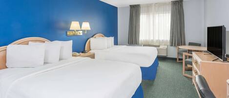 A hotel room with two beds, a desk, a chair, a TV, and a window with curtains.