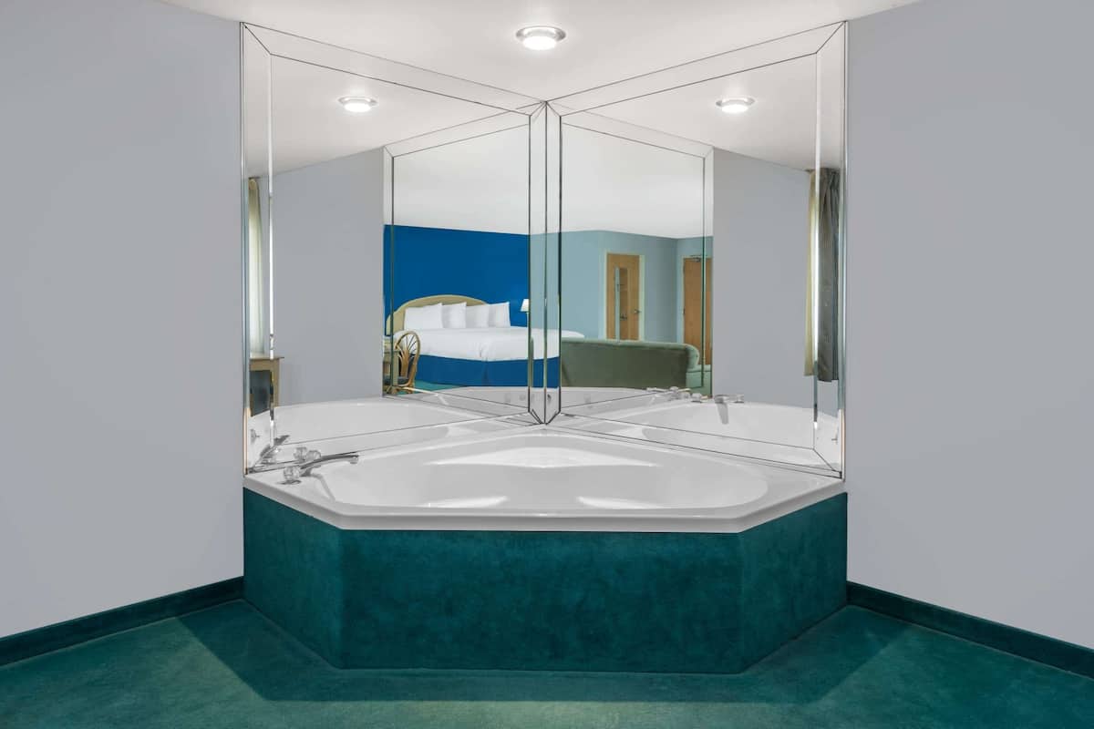 Ein modernes Badezimmer mit einer freistehenden Badewanne, einem großen Spiegel und einer blauen Akzentwand.