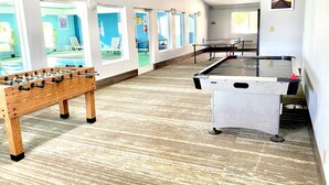 A room with two foosball tables, a ping pong table, and a pool table.