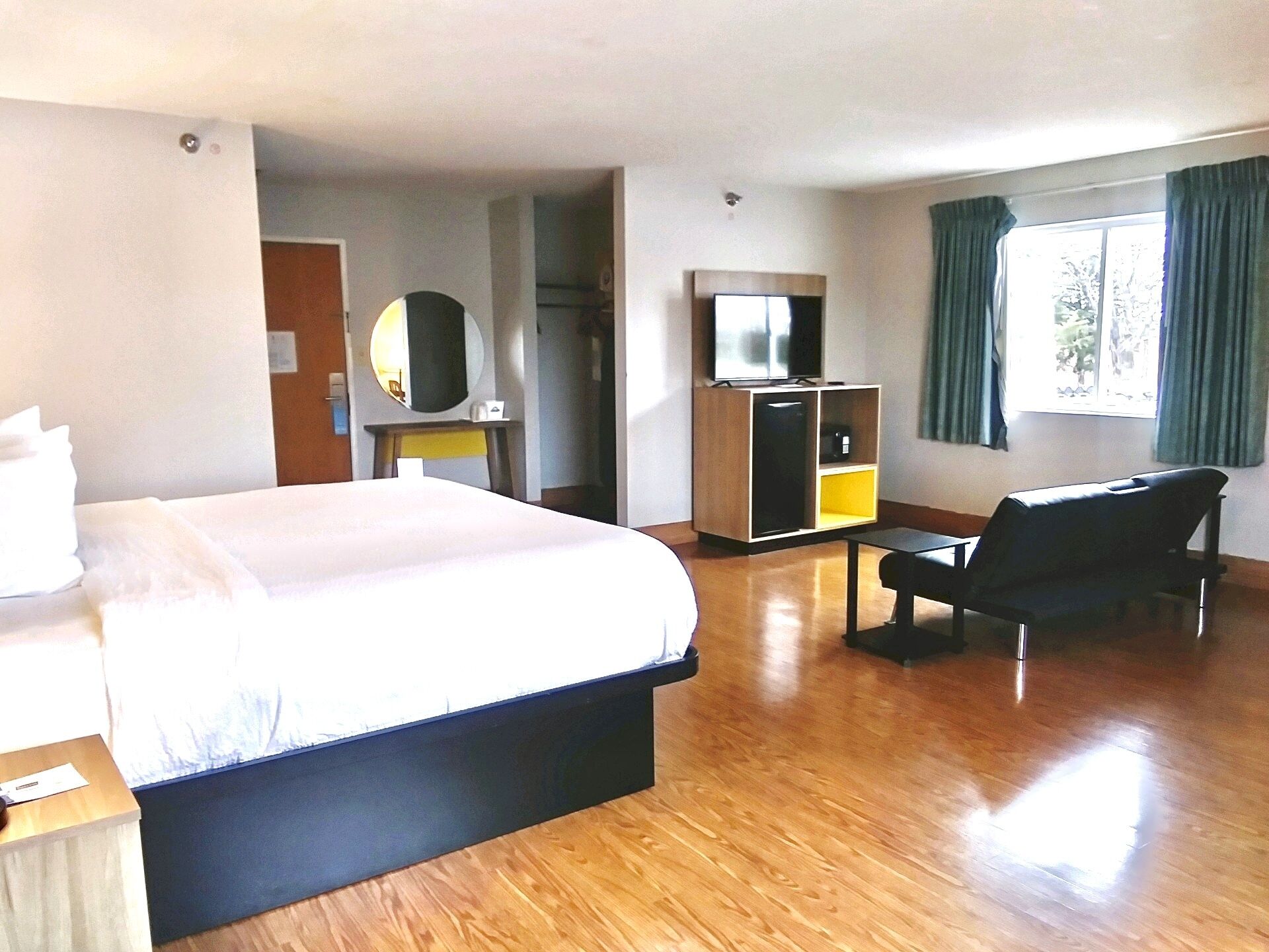 A hotel room with a bed, a desk, a chair, a TV, and a wardrobe.